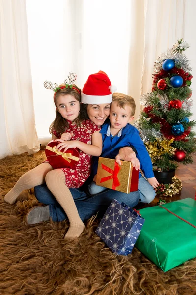 Молодая мать в шляпе Санта-Клауса с сыном и дочерью — стоковое фото