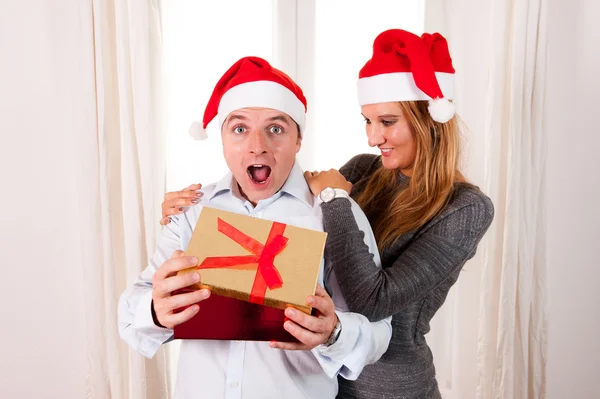 Joven pareja feliz con regalos en la alfombra en Navidad — Foto de Stock