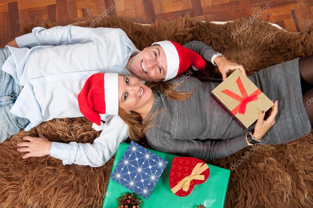 Young Happy Couple with Presents on rug at Christmas