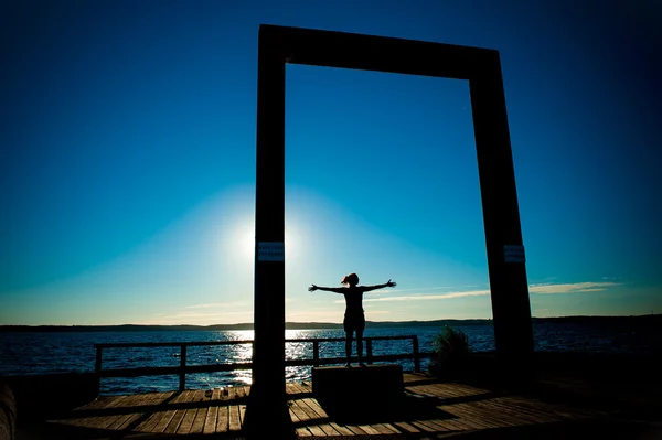 Junge Frauensilhouette mit offenen Armen zum Meer — Stockfoto