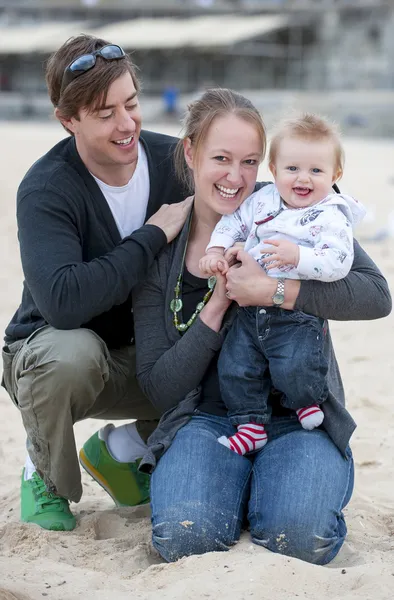 Ungt par på stranden sand med baby — Stockfoto