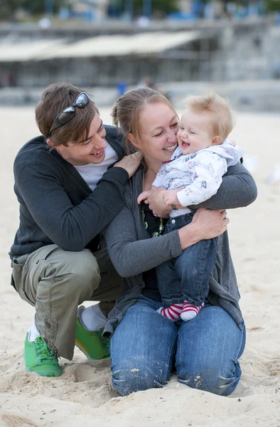 Ungt par på stranden sand med baby — Stockfoto