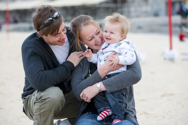 Pareja joven en la playa de arena con bebé — Foto de Stock