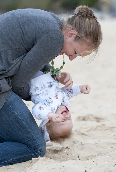 年轻的母亲抱着婴儿在沙滩上玩 — 图库照片