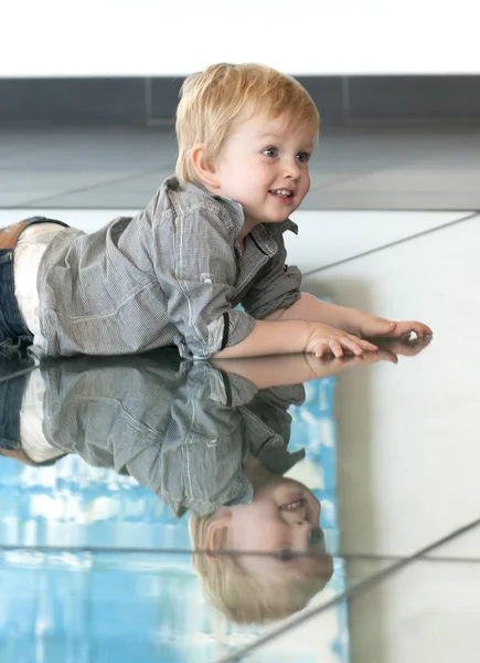 Bambino che gioca con la sua riflessione sul pavimento — Foto Stock