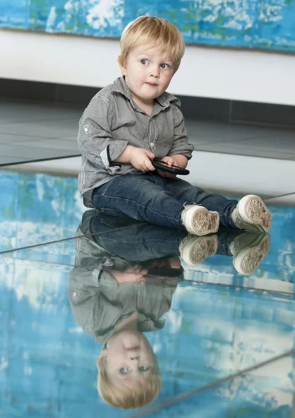 Little child playing with cellphone and his reflexion on the floor — Stock Photo, Image