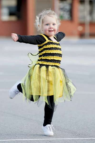 Liten blond flicka i bee kostym dancing utomhus — Stockfoto