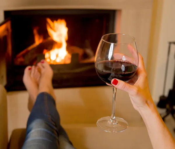 Mujer bebiendo vino frente al fuego — Foto de Stock