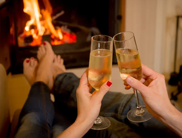 Couple drinking champagne in front of a fire — Stock Photo, Image