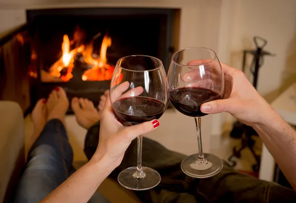 Pareja bebiendo vino delante de un fuego — Foto de Stock