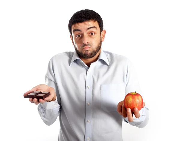 Hombre atractivo sosteniendo chocolate y manzana — Foto de Stock