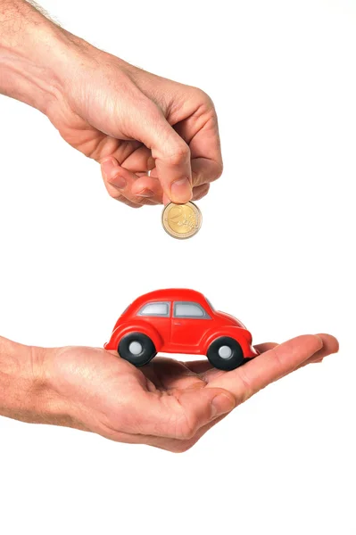 Man inserting coin into mini car piggy bank — Stock Photo, Image