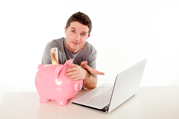 Homem com banco porquinho e laptop pensando em salvar on-line — Fotografia de Stock