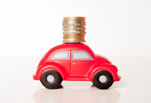 Красный автомобиль игрушки на белом фоне с монетами на крыше — стоковое фото
