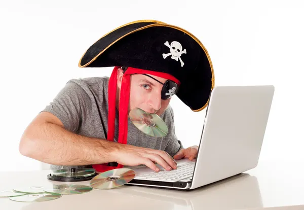 Man in pirate hat downloading music on a laptop — Stock Photo, Image