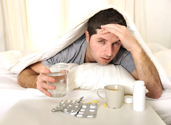 Mann mit Kopfschmerzen und Kater mit Tabletten im Bett — Stockfoto