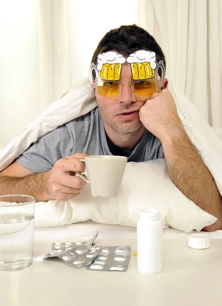 Mann mit Kopfschmerzen und Kater mit Tabletten im Bett — Stockfoto