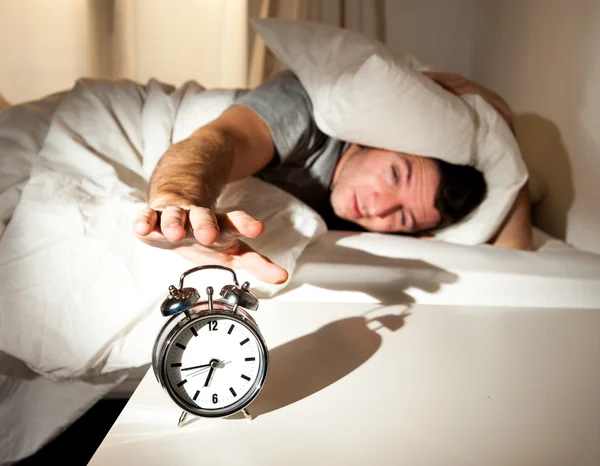 Sleeping man disturbed by alarm clock early morning — Stock Photo, Image