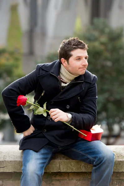 Uomo con cioccolatini e una rosa in piedi — Foto Stock