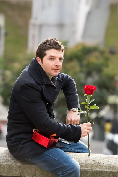 Uomo con cioccolatini e una rosa in piedi — Foto Stock
