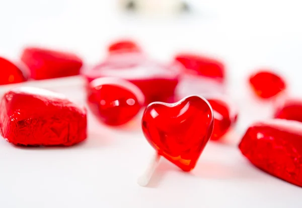 Macro red heart with chocolates and lollipops on white background — Stock Photo, Image
