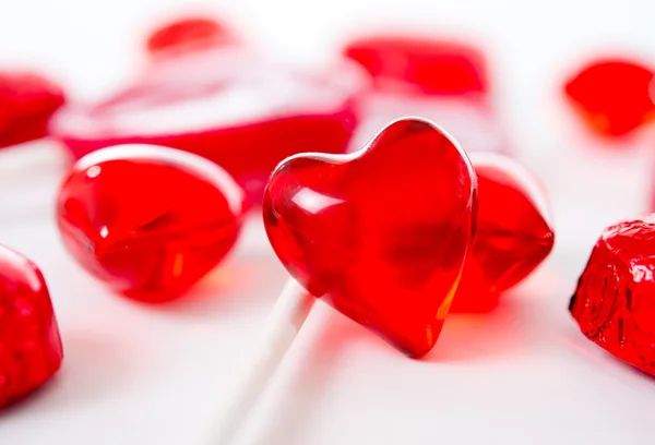 Macro red heart with chocolates and lollipops on white background — Stock Photo, Image