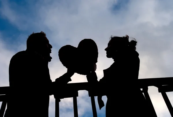 Atractiva pareja en Silhouette sosteniendo un corazón de amor —  Fotos de Stock