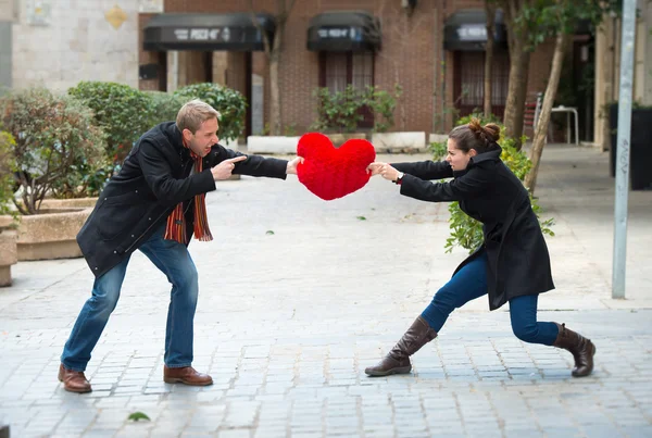 Attraktivt par som slåss om en kärlek hjärtat kudde — Stockfoto