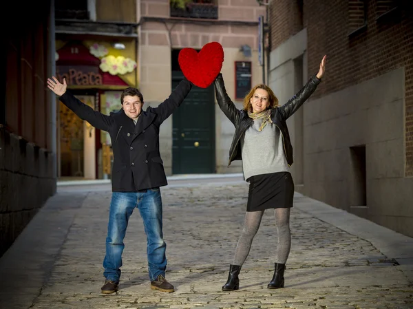 Attractive couple smiling with a big red heart — Stock Photo, Image