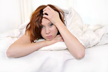 red hair woman on bed waking up with hangover and headache clipart