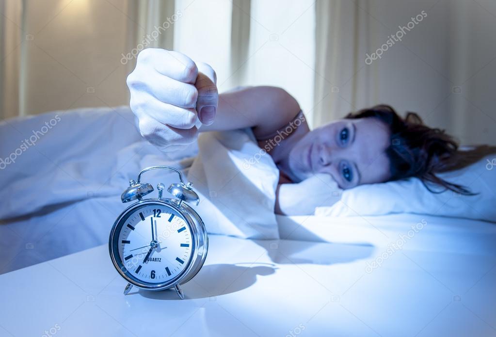 close up alarm clock with red haired woman turning it off