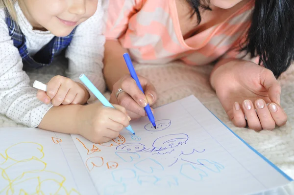 Close up young Mother and adorable little daughter lying on bed and drawing together — Stock Photo, Image
