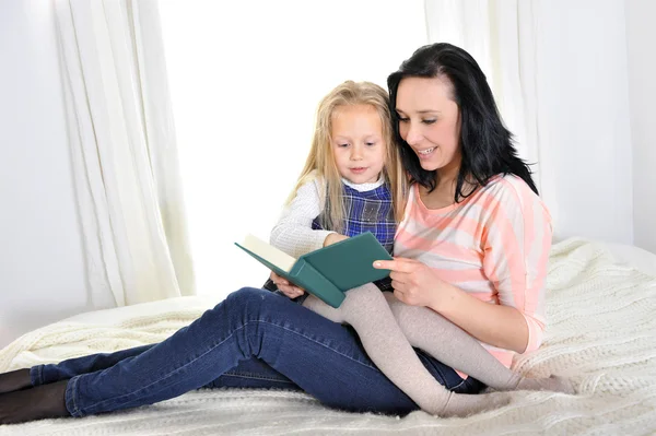 Attractive woman with beautiful daughter reading book — Stock Photo, Image