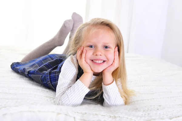 Entzückendes blondes blauäugiges kleines Mädchen liegt glücklich auf dem Bett — Stockfoto