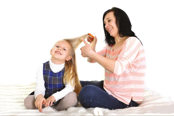 Jonge mooie moeder met haarborstel dochter blonde haren borstelen — Stockfoto