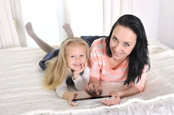 Glückliche junge Mutter und kleine entzückende blonde Tochter mit Tablette — Stockfoto