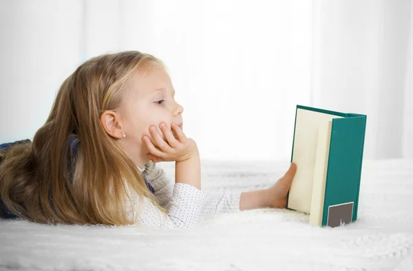 Happy cute blonde hair blue eyed school girl reading a book — Stock Photo, Image
