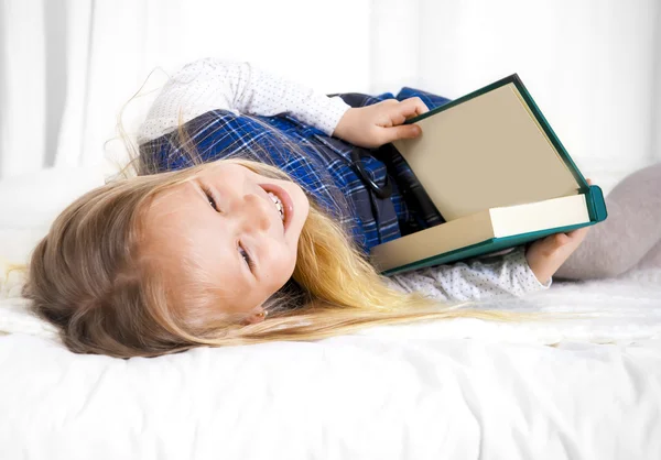Happy cute blonde hair school girl reading a  lying on bed sofa — Stock Photo, Image