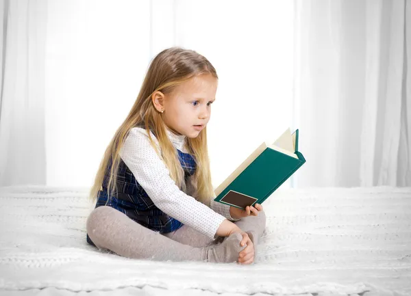 Scared cute blonde haired school girl reading a book — Stock Photo, Image
