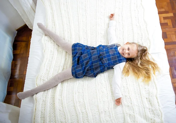Happy cute blonde haired girl on a white bed — Stock Photo, Image
