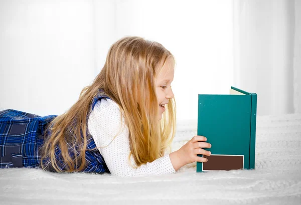Happy cute blonde haired school girl reading a book — Stock Photo, Image