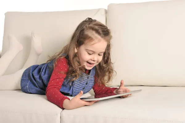 Sweet Little Girl lying on Couch playing with Digital Pad — Stock Photo, Image