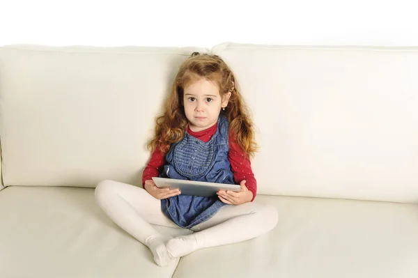 Dulce niña acostada en el sofá jugando con almohadilla digital — Foto de Stock