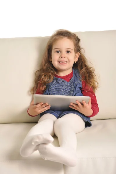 Doce menina deitada no sofá jogando com almofada digital — Fotografia de Stock