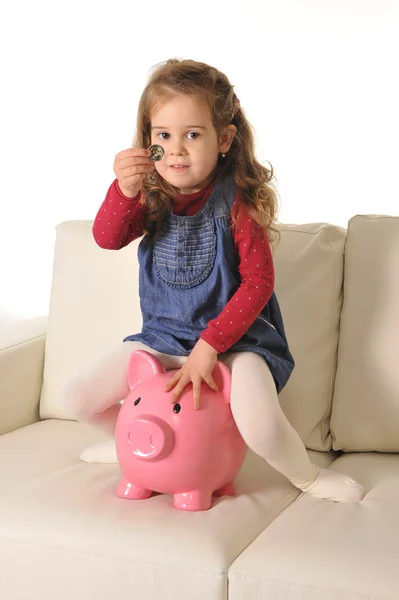 Happy Cute little girl sitting on huge piggy bank inserting Coin — Stock Photo, Image