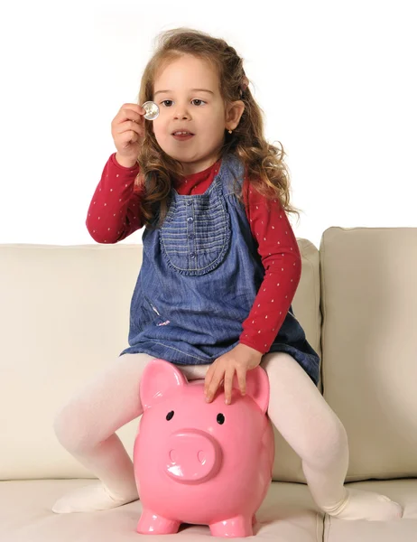 Glad söt liten flicka sitter på enorma spargris infoga mynt — Stockfoto