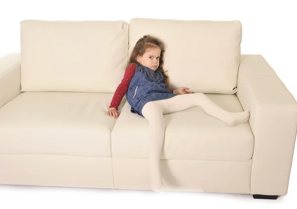 Gadis kecil yang manis bahagia dengan rambut panjang berbaring di sofa bermain-main — Stok Foto
