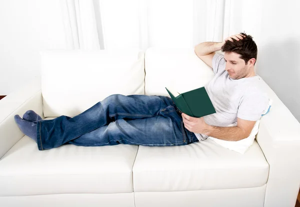 Attractive man reading book or studying on couch — Stock Photo, Image