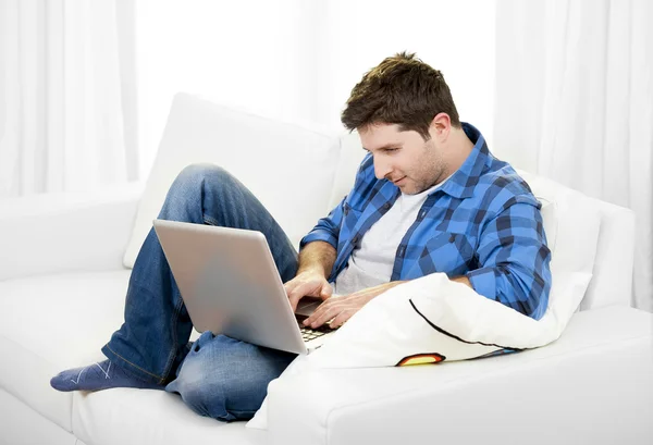 Привабливий чоловік з комп'ютером, сидячи на дивані — стокове фото
