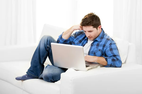 Atrakcyjny mężczyzna z komputera siedząc na kanapie — Zdjęcie stockowe